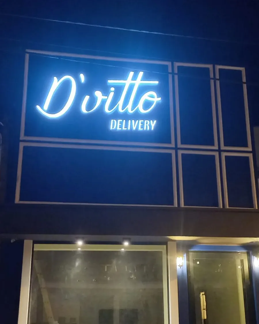 Letreiro do Armazém D'Vitto aceso à noite, com as letras em luz branca