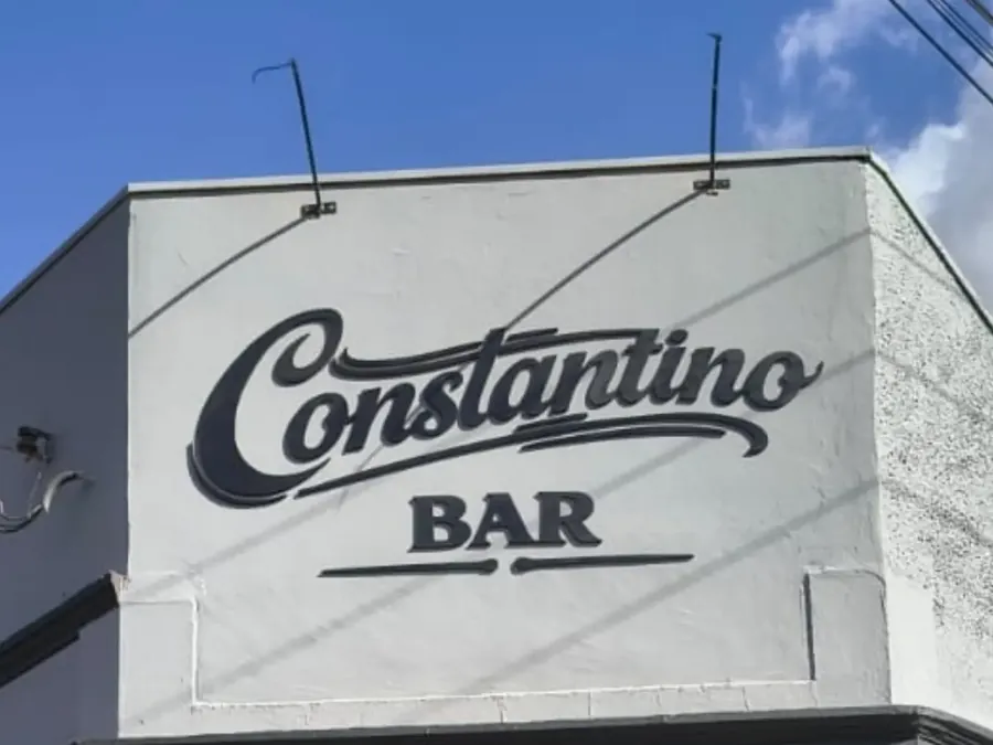 Letreiro cursivo do Constantino Bar na fachada branca