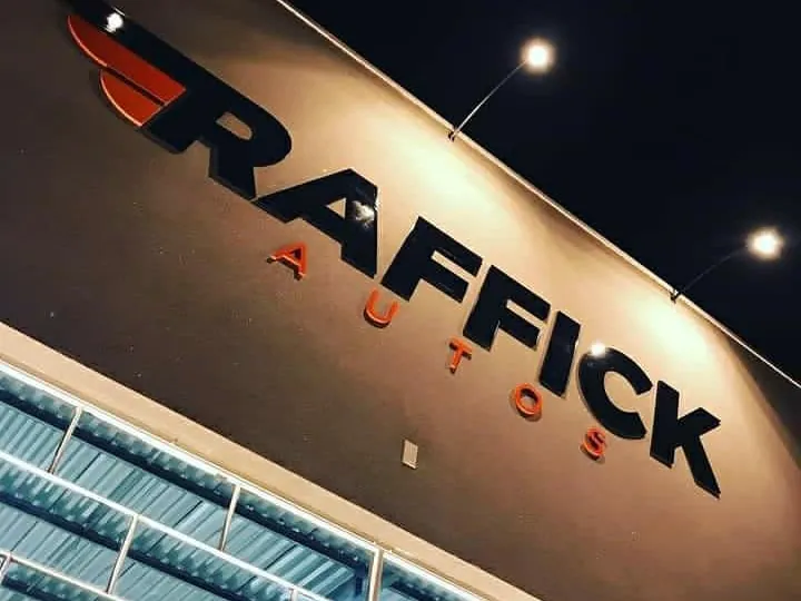 Letreiro da Raffick Autos iluminado à noite na fachada inclinada